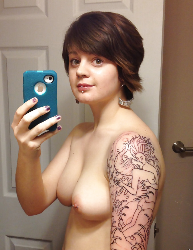 Selfie jeune brune cheveux courts piercée et tatouée sur le bras